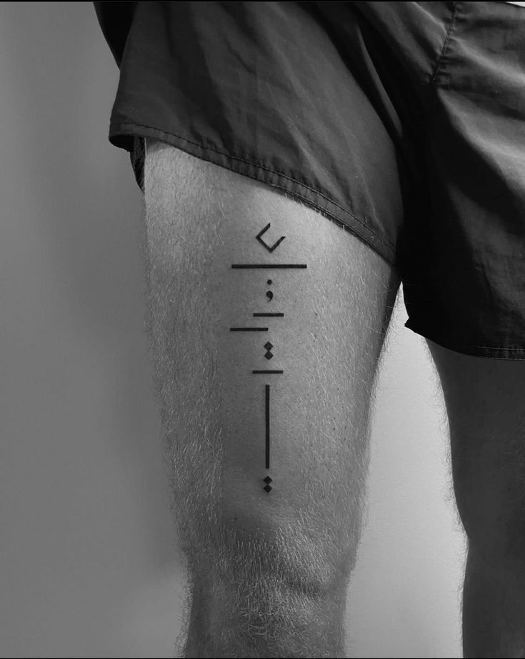 a black and white photo of a man's leg with an arrow tattoo on it