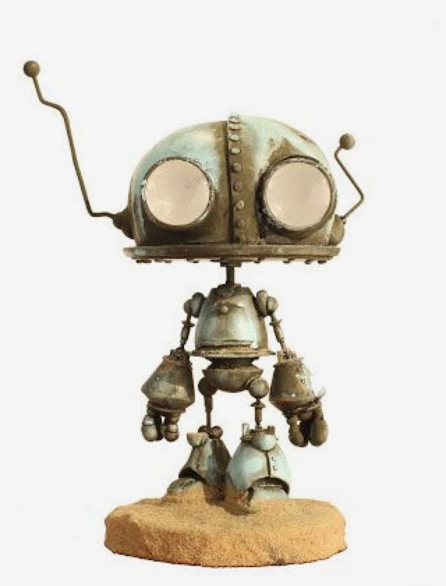 an old metal robot with two bells on it's head and eyes, standing in front of a white background