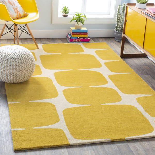 a bright yellow rug with white circles on it in a living room next to a chair