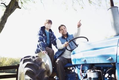 two people riding on the back of a tractor