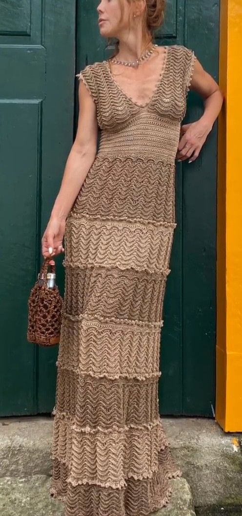 a woman standing in front of a green door wearing a dress and holding a purse