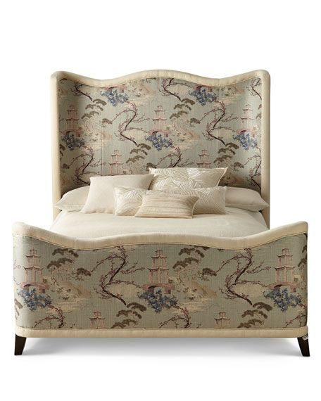 an upholstered bed with pillows and decorative wallpaper on the headboard is shown