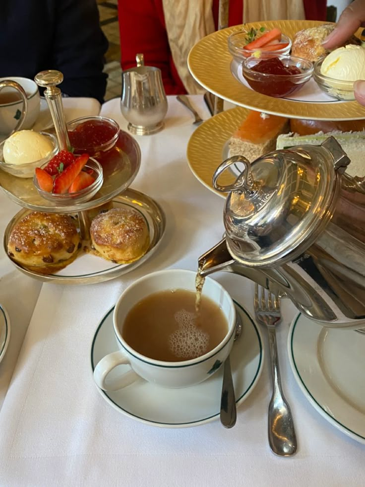 a table with tea, pastries and silverware on it in a fancy setting