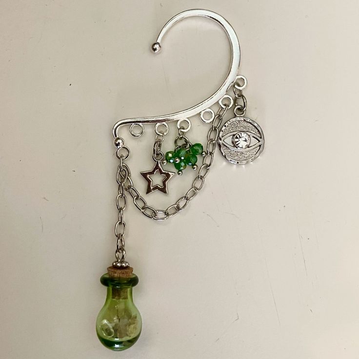 A Dangling, Silver Ear Cuff With Multiple Magical Charms Attached. Inside The Little Bottle, There Are Small Pieces Of Different Real Gemstones Including Opal, Amethyst, Jade, And Quartz! Handmade By Me, Setrosestudios Ear Cuff Ideas, Green Accessories Aesthetic, Ren Faire Earrings, Green Witch Fashion, Fairy Costume Jewelry, Fairycore Drop Earrings With Ear Wire, Whimsical Green Jewelry With Charms, Handmade Green Fairy Jewelry, Elf Ear Jewelry