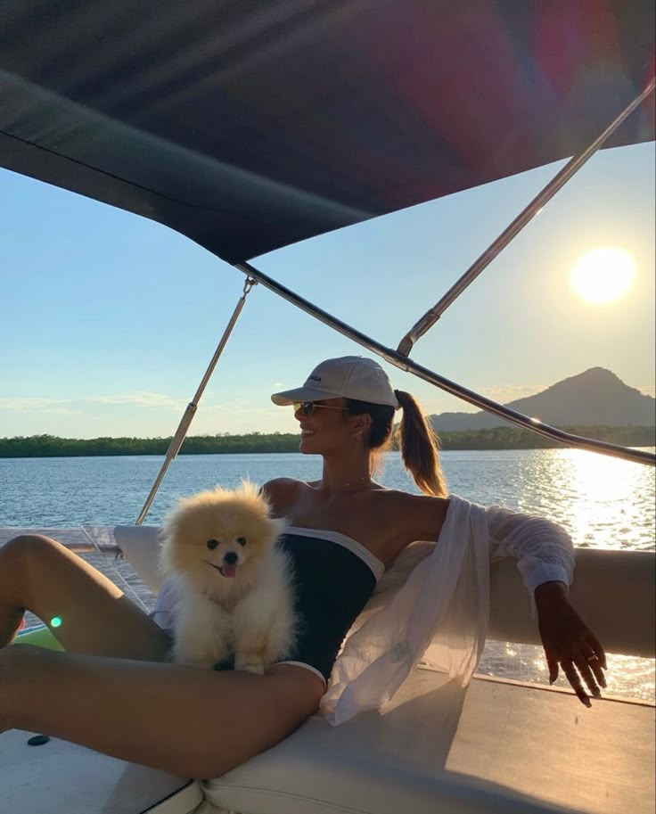 a woman sitting on the back of a boat holding a small dog in her lap