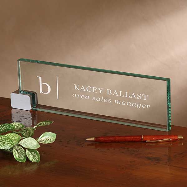 a glass sign sitting on top of a wooden table next to a pen and plant