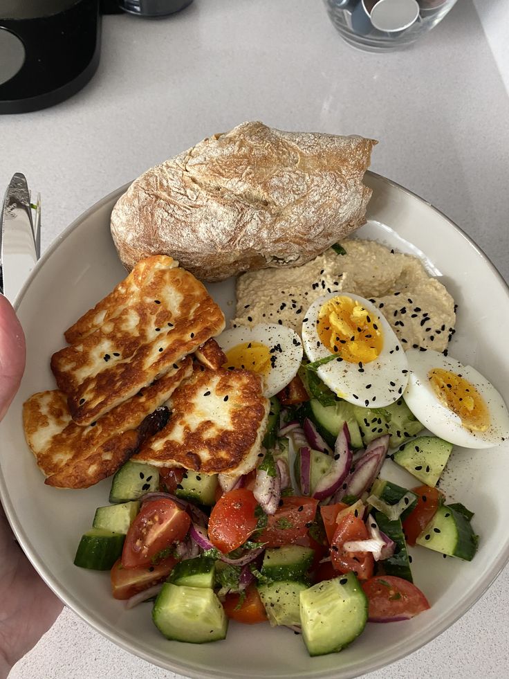 a white plate topped with lots of different types of food next to a bagel