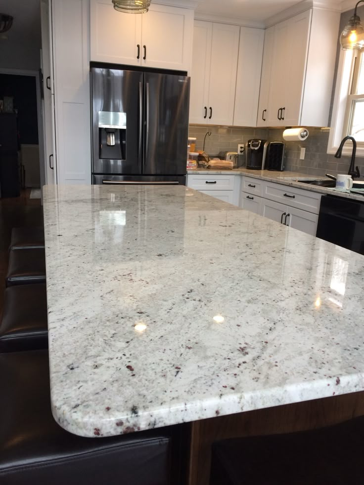 a kitchen with an island in the middle and white cabinets on both sides, along with stainless steel appliances