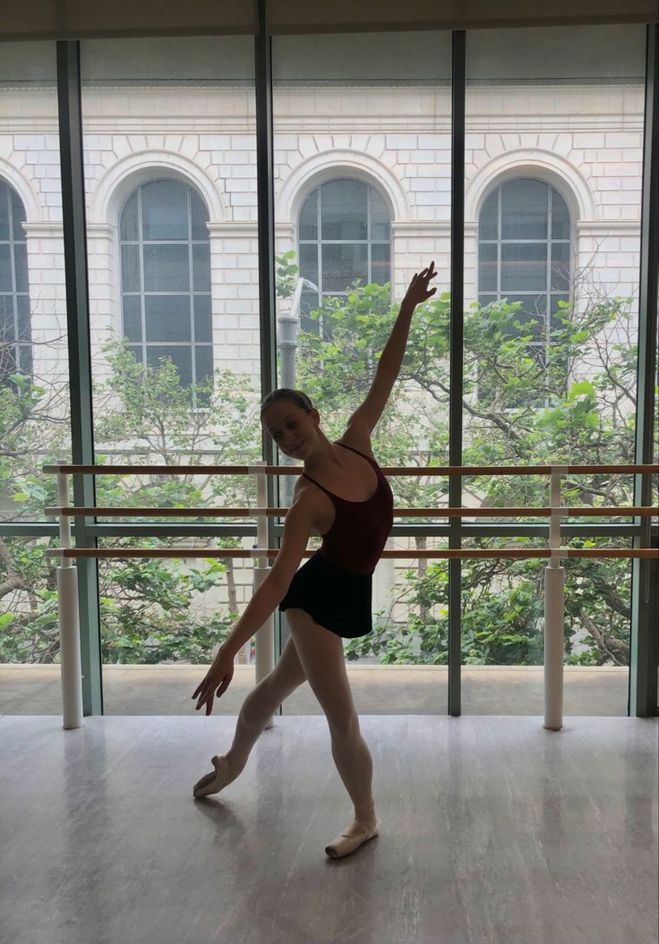 a ballerina is standing on one leg in front of a window