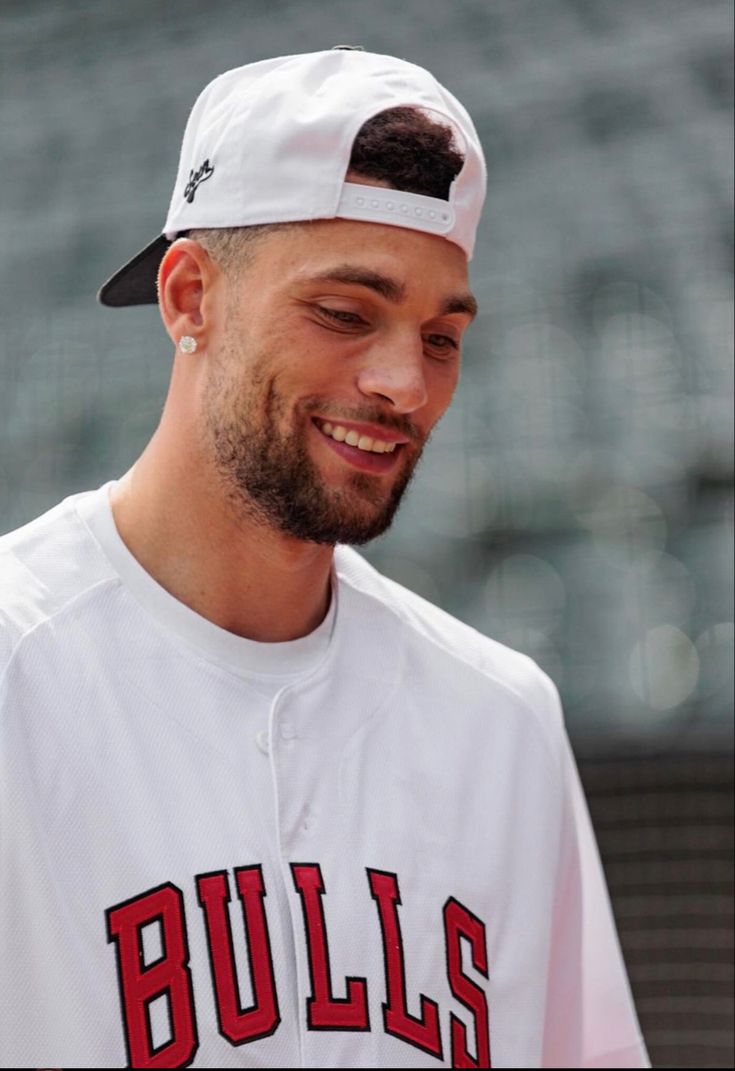 a baseball player is smiling and wearing a white uniform with red lettering on the front