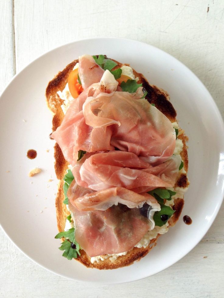 an open face sandwich with ham and cheese on toasted bread, garnished with parsley