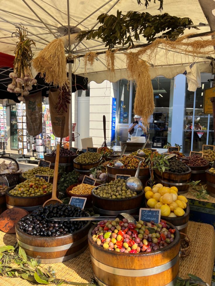 an open air market with lots of different types of fruits and vegetables in wooden buckets