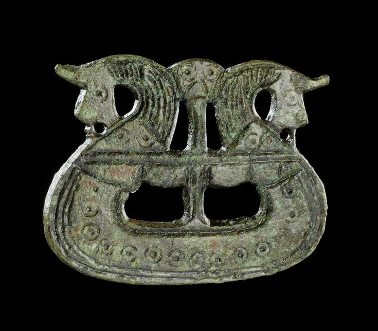 an old metal object with two animals on it's back end, against a black background