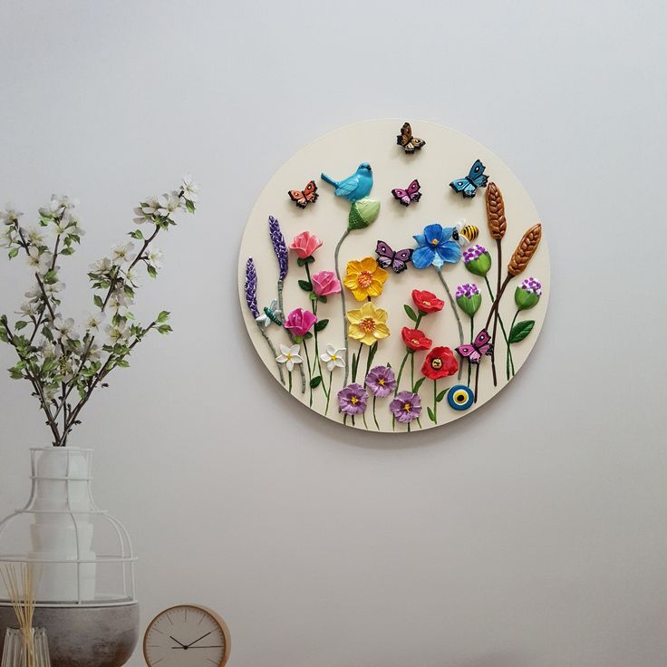 there is a wall decoration with flowers and birds on it in the corner next to a vase