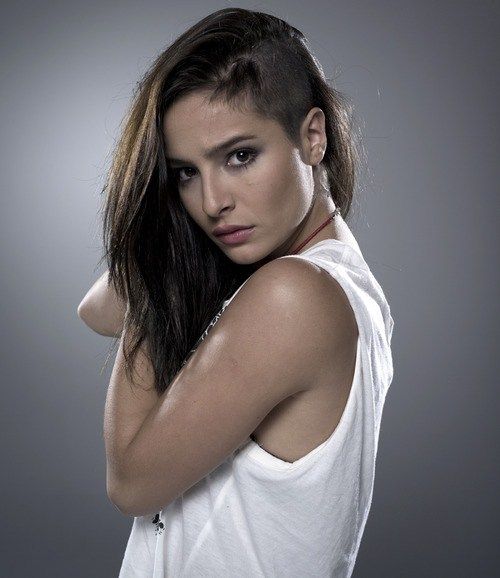 a woman with long hair posing for a magazine cover photo, she is wearing a white top and has her arms behind her head