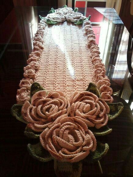 a crocheted table runner with roses on it