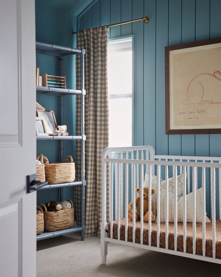 a baby's crib in a blue room with bookshelves and baskets