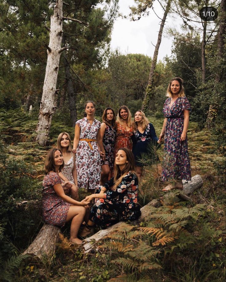 a group of women standing next to each other on a forest floor covered in trees