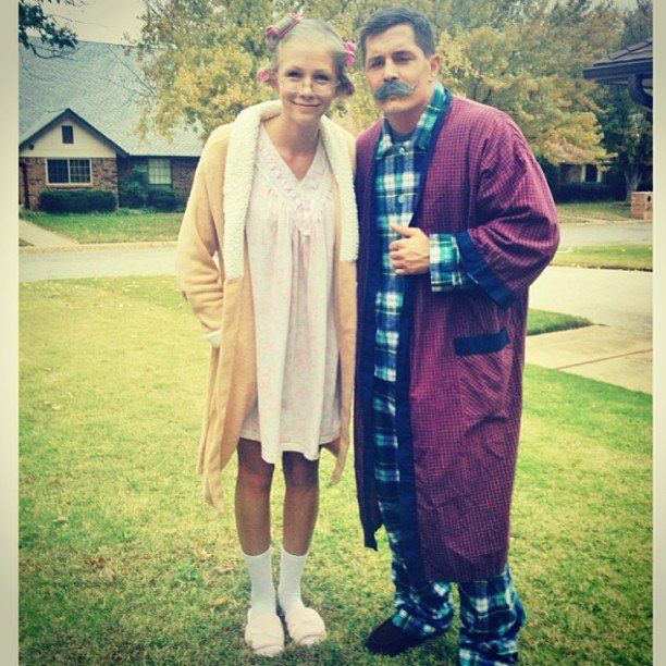 the man and woman are dressed up for halloween outside in their pajamas, with one wearing a fake moustache on his face