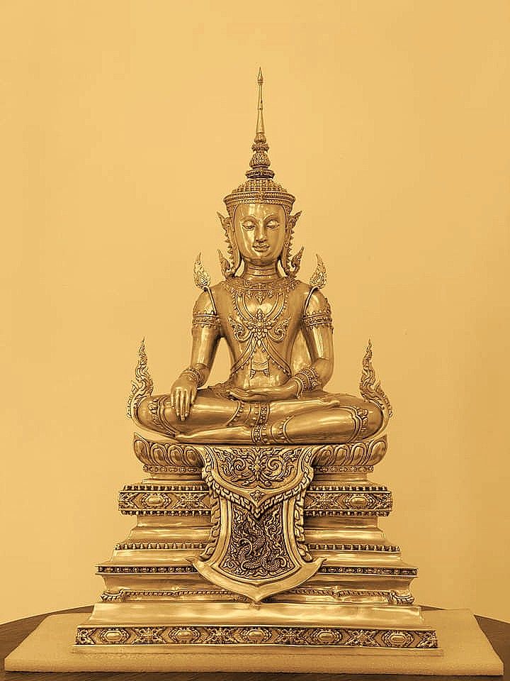 a golden buddha statue sitting on top of a wooden table