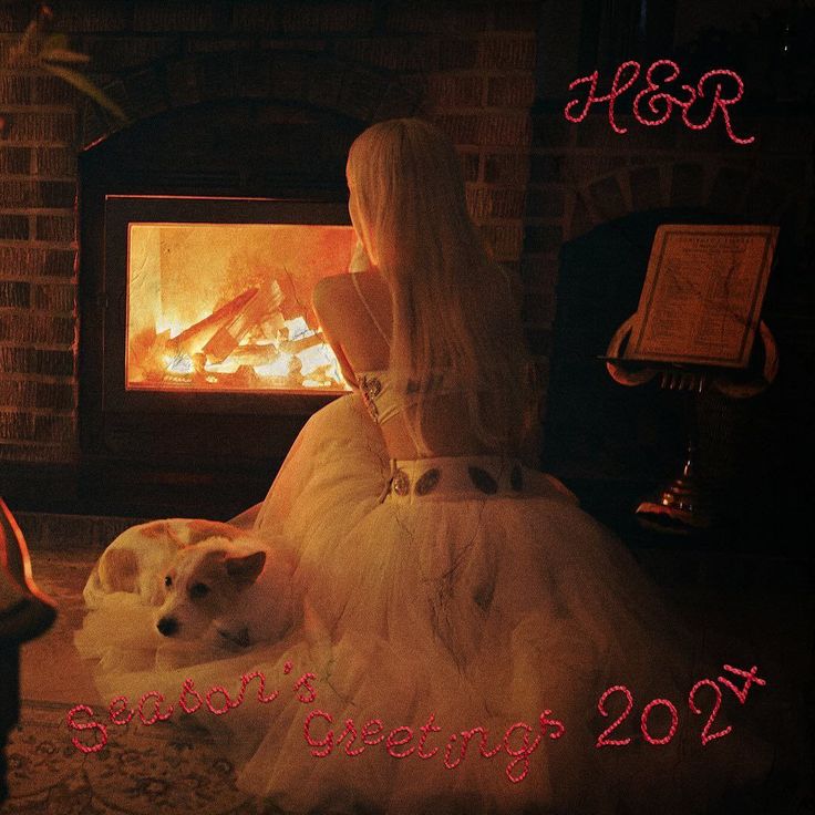 a woman in a white dress sitting next to a dog on the floor near a fireplace