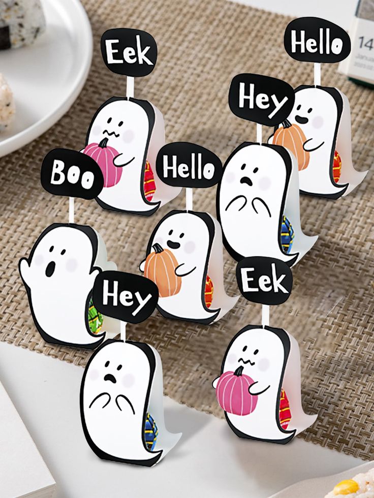 a group of ghost place cards on top of a table with food in the background