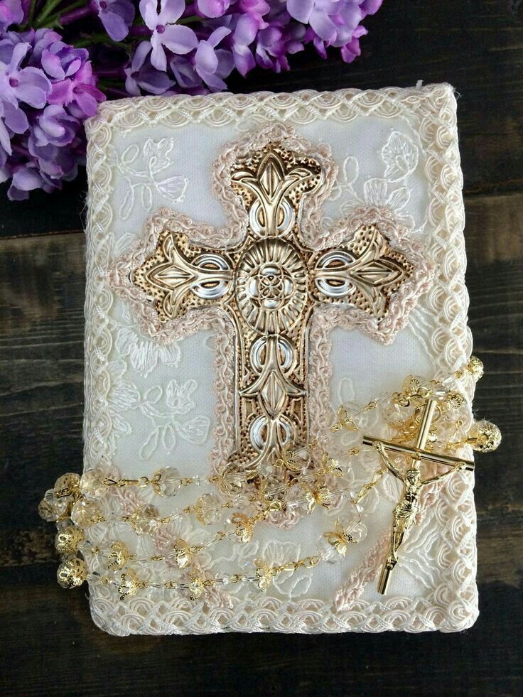 an ornate cross is on top of a doily with purple flowers in the background