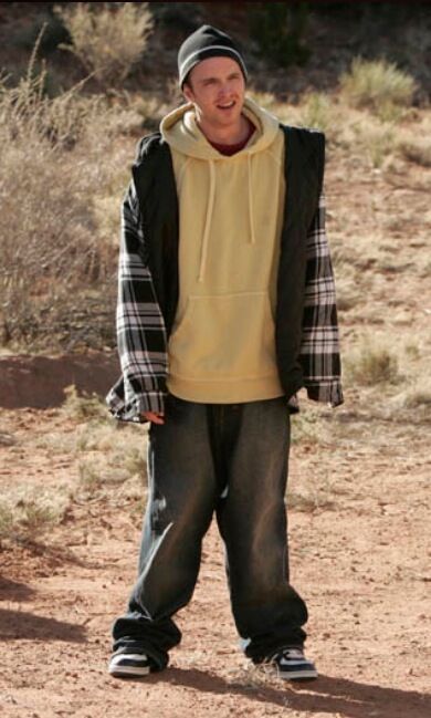 a young man standing in the dirt with his hands on his hips and smiling at the camera