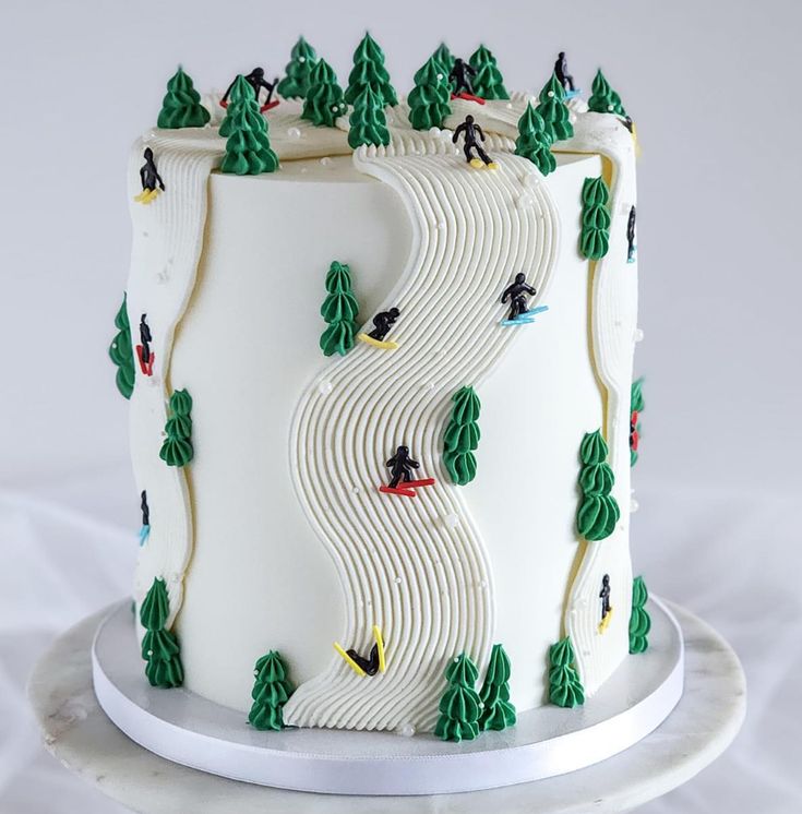 a white cake decorated with trees and skiers