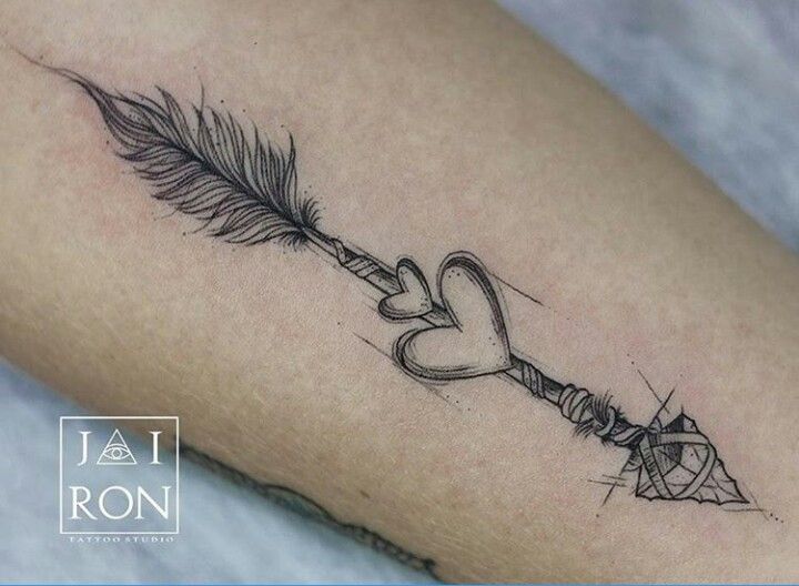 a tattoo on the leg of a woman with a feather and heart shaped key attached to it