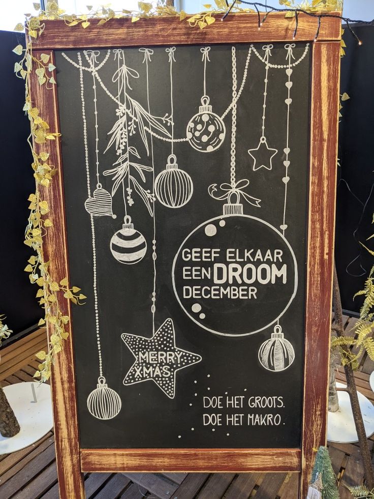 a chalkboard sign with ornaments hanging from it's sides and the words geep elkaar een droom december