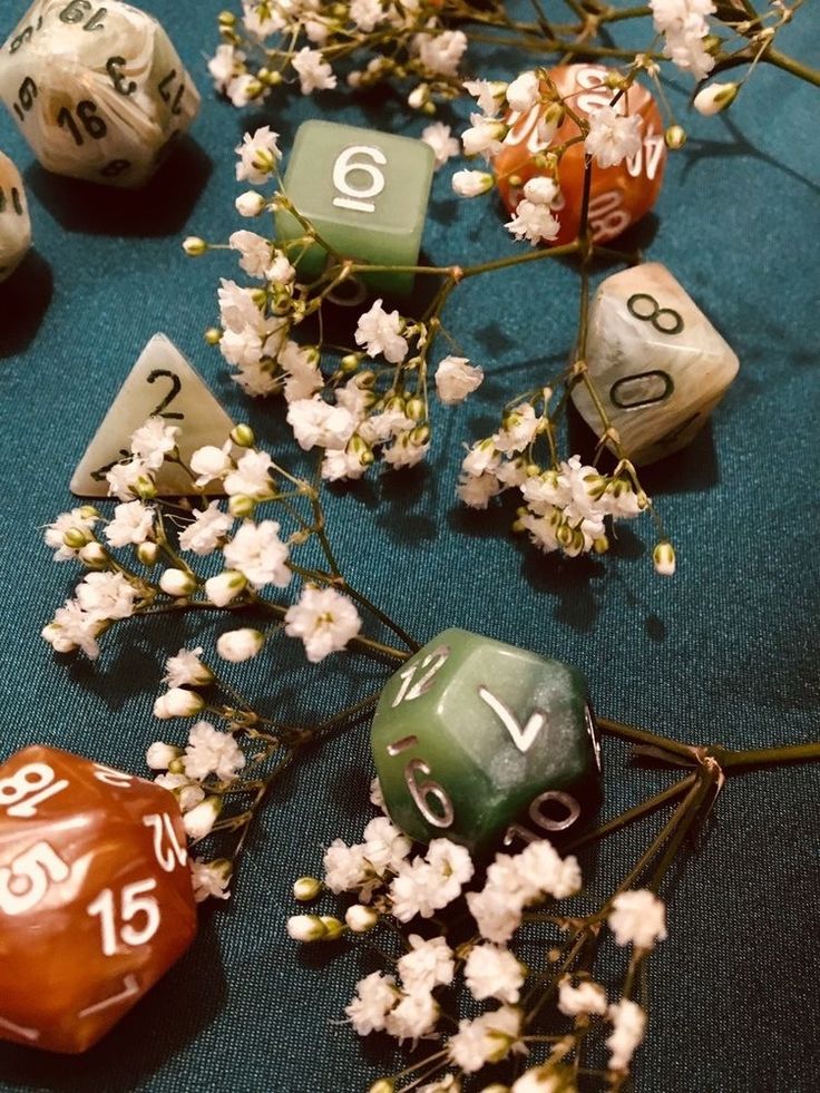 several different colored dices and flowers on a blue table cloth with numbers written on them