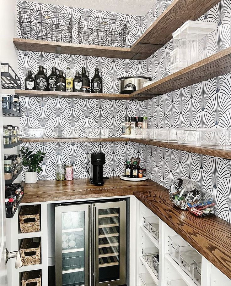 a kitchen with shelves and wine bottles on top of the counter, in front of an art deco wallpaper