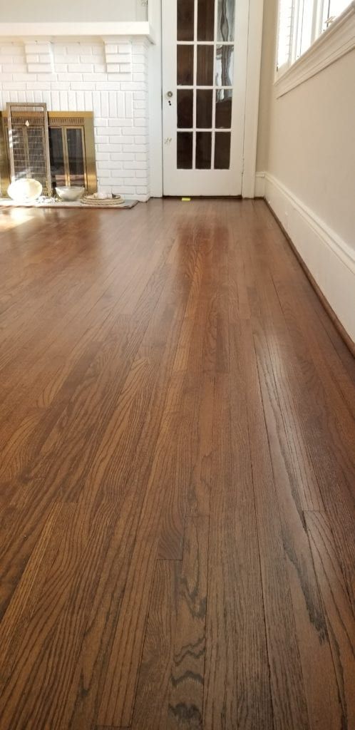 an empty living room with wood floors and white fireplace in the corner, looking into the front door