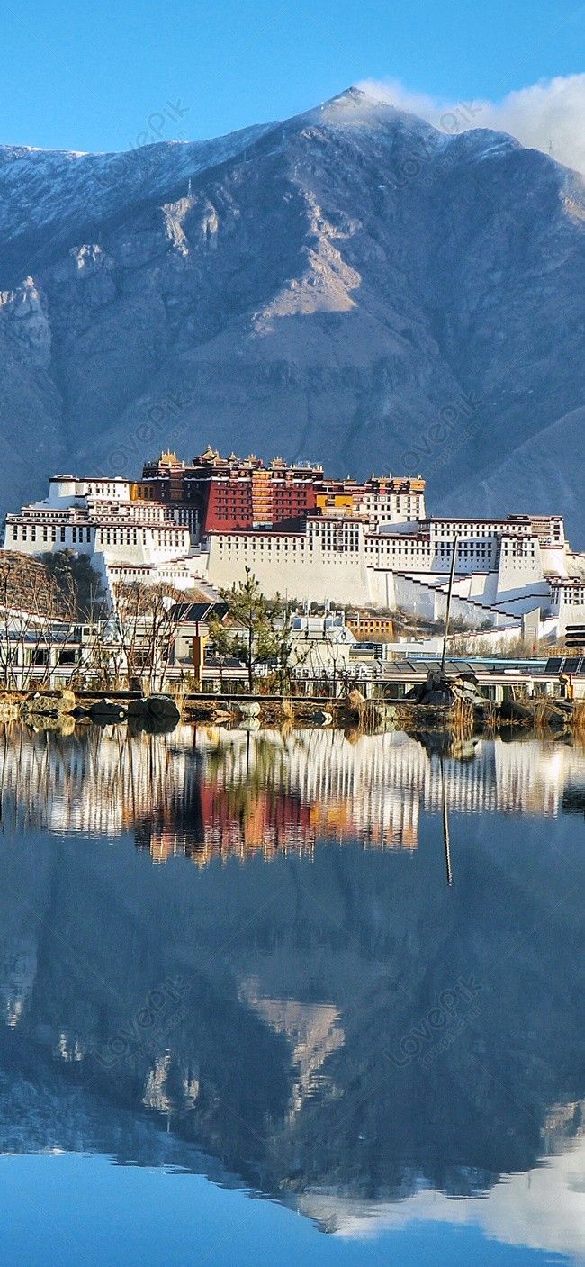 a large white building sitting on top of a mountain next to a body of water