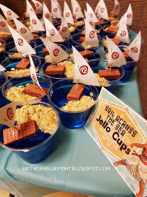 a table topped with cups filled with cereal and small sailboats on top of them