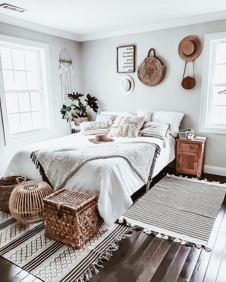 a bedroom with white walls and wood flooring is pictured in this image, there are wicker baskets on the bed