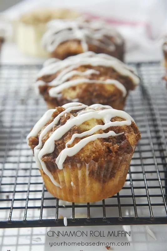 there are many muffins on the cooling rack and one is drizzled with icing