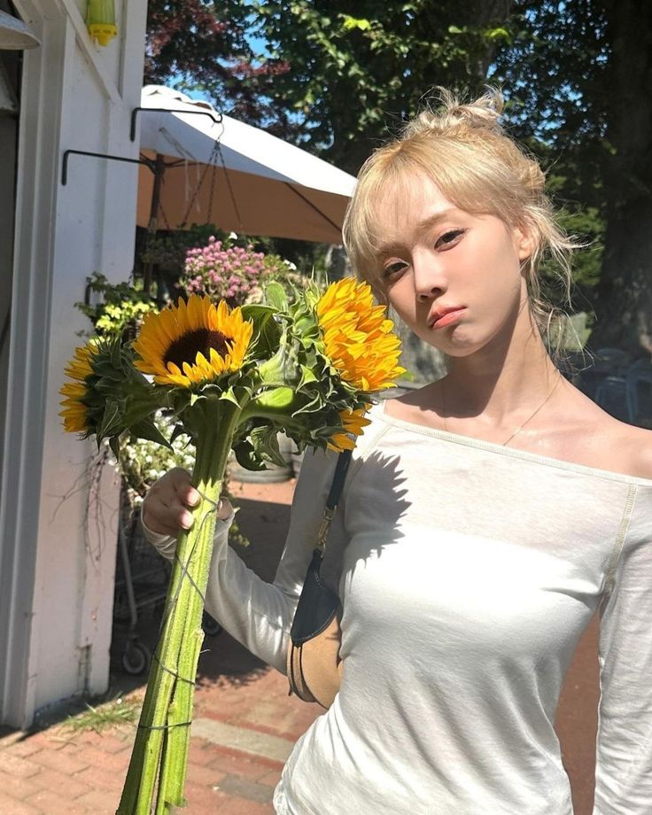 a woman holding a bouquet of sunflowers in front of her face