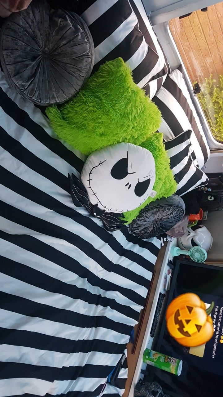 a green stuffed animal laying on top of a bed next to a halloween pumpkin and other items