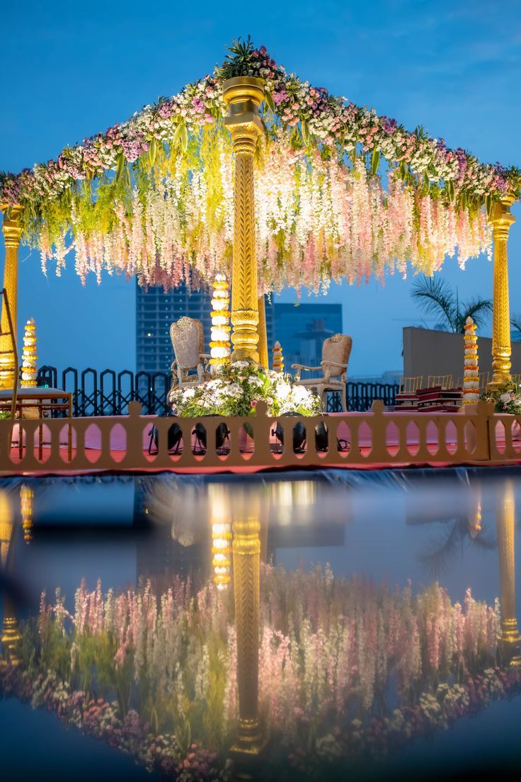 an elaborate gazebo decorated with flowers and greenery on the water's edge