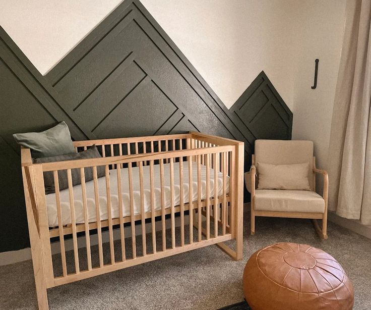 a baby's room with a crib, chair and ottoman in the corner