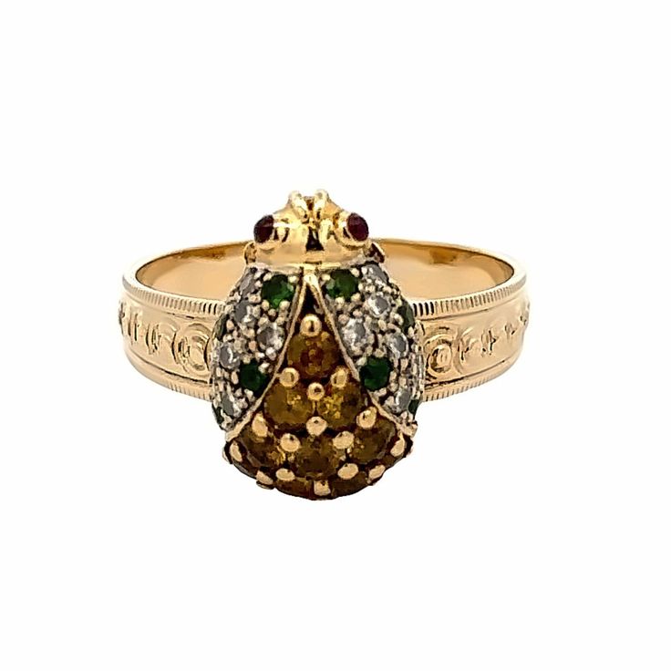 a gold ring with green and white stones on it's sides, sitting in front of a white background