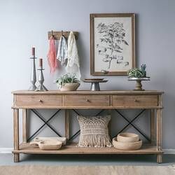 a wooden table topped with two vases next to a wall mounted planter and potted plants