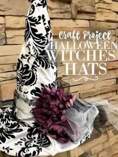 a black and white halloween hat with purple flowers on the top, sitting next to a brick wall