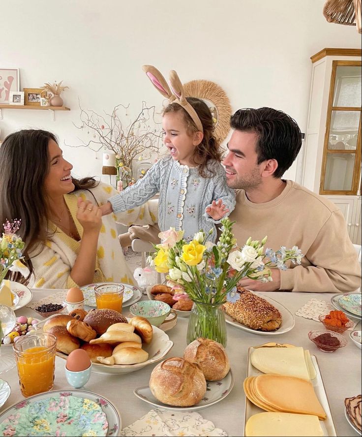 a family sitting at a table with food and drinks in front of them on easter day