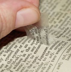 a close up of a person reading a book with their thumb on the edge of an open book