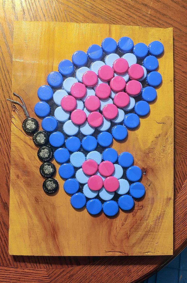 a wooden table topped with blue, pink and black buttons on top of a piece of wood