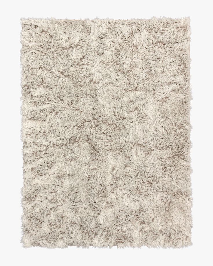 an area rug with white and gray shaggys on the top, in front of a white background