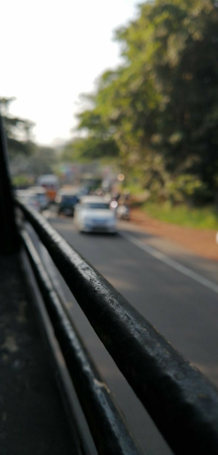 cars driving down the road with trees in the backgrouund and traffic behind them